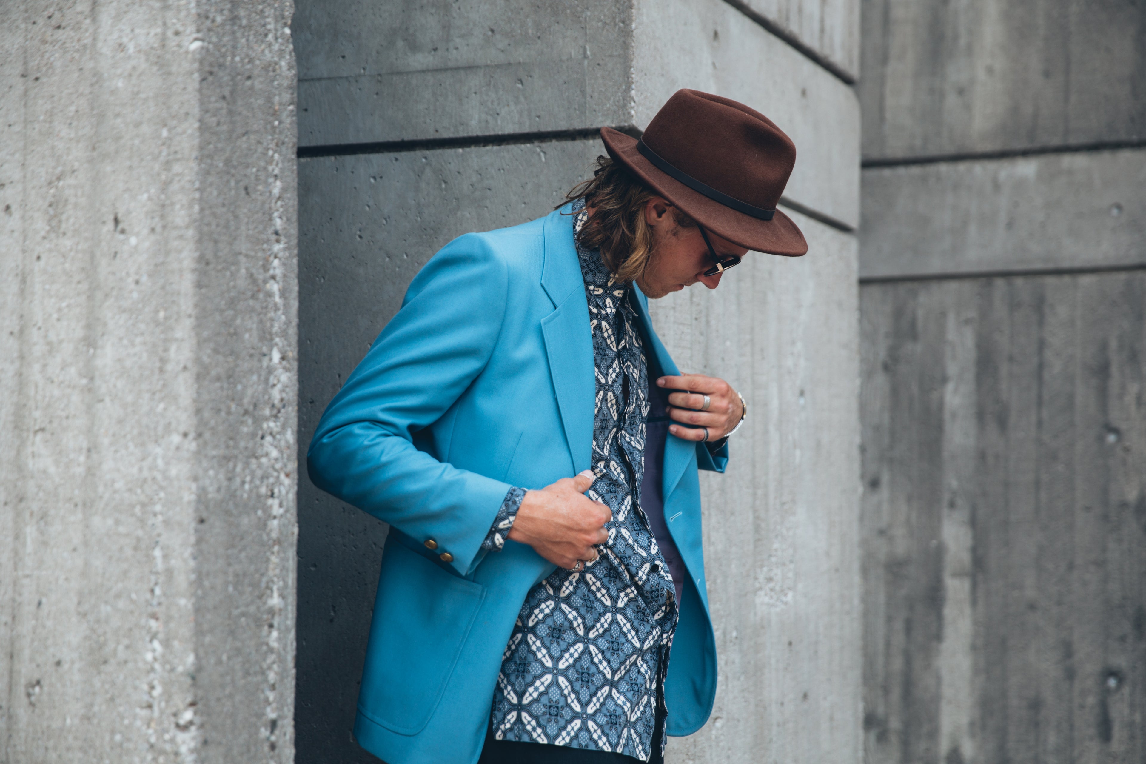 Man in blue jacket and patterned shirt holding his lapels.